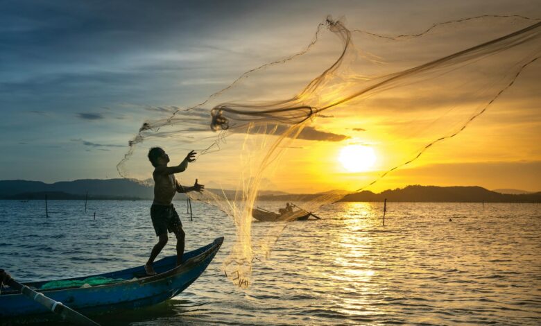 fisherman throwing fish net on lake